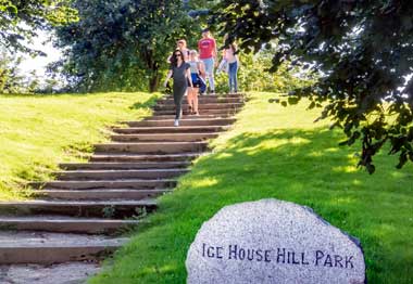 Sunny afternoon in Ice House Hill Park. A family can be seen walking down a path